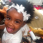 Parfaite Grâce Olga a rejoint le concours — aidez-le/la à gagner de superbes lots ! adult_hand, afro_hair, baby, bracelet, child, closeup, cute, fabric, hand, happy, headband, indoor, infant, jewelry, person, portrait, skin, smiling, table, white_clothing