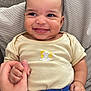 baby, smiling, hand_holding, cushion, shirt, pants, patterned_clothing, infant, happy, cheeky, face, expression, person, cute, indoors, closeup, skin, hair, seated, comfort