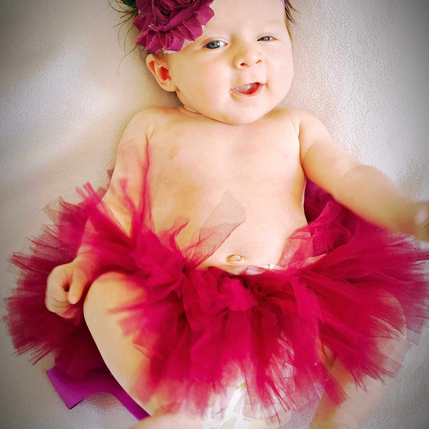 Louise a rejoint le concours — aidez-le/la à gagner de superbes lots ! baby, baby_girl, bare_skin, cheeks, child, closeup, clothing_accessory, cute, diaper, face, flower, happy, headband, infant, lying_down, maroon, portrait, smiling, soft_texture, tutu