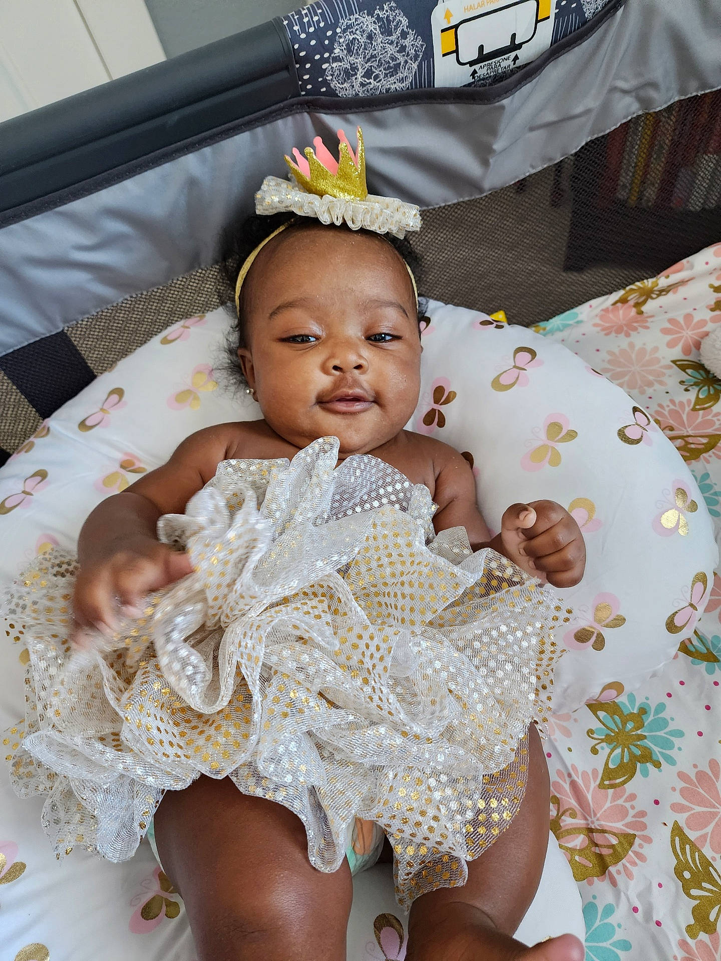 Skylar is registered to the contest to win money with this photo: baby, baby_toddler_clothing, bridal_accessory, chair, comfort, dress, embellishment, event, eye, face, fashion_accessory, fashion_design, hair_accessory, happy, headgear, headpiece, linens, person, sitting, thigh