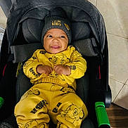 Ryan Tavares a rejoint le concours — aidez-le/la à gagner de superbes lots ! baby, child, smiling, yellow_clothing, lion_king, beanie, car_seat, indoor, happy, cute, infant, portrait, clothing, socks, floor, tile_floor, wood_floor, toy, seat_belt, fabric