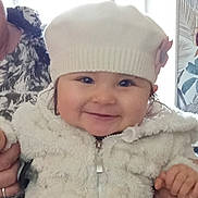 Eva participe au concours pour gagner de l'argent avec cette photo : apparel, baby, child, closeup, cute, face, flower, hands, happy, hat, holding, indoor, infant, person, portrait, smile, warm, warm_clothes, white_jacket, winter_clothing