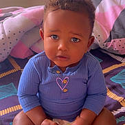 Sadam participe au concours pour gagner de l'argent avec cette photo : toddler, child, baby, bed, blanket, pillow, indoors, blue_clothing, diaper, curly_hair, skin, face, hands, sitting, cute, expression, portrait, colorful, soft_lighting, comfort