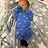 baby, infant, sleeping, pacifier, blue_outfit, onesie, cloud_pattern, blanket, star_pattern, bed, lying_down, portrait, face, closed_eyes, home, cozy, textile, black_socks, head, child