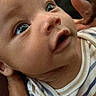 Monty joined the competition — help win amazing prizes! baby, infant, child, close_up, portrait, wide_eyed, lying_down, being_held, adult_hands, striped_clothing, onesie, face, eyes, nose, mouth, cheeks, indoor, bedding, family, adorable