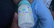 Monty is registered to the contest to win money with this photo: baby, infant, child, bottle, feeding, pacifier, blue_outfit, striped_cap, hat, sleepy, portrait, close_up, face, eyes, adult_hand, indoor, soft_lighting, blanket, baby_clothing, cozy