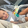 Jahkai joined the competition — help win amazing prizes! baby, child, infant, smiling, happy, curly_hair, car_seat, vehicle, safety_harness, teething_toy, pacifier, toy, gray_clothing, blanket, seated, indoors, sunlight, portrait, close_up, family