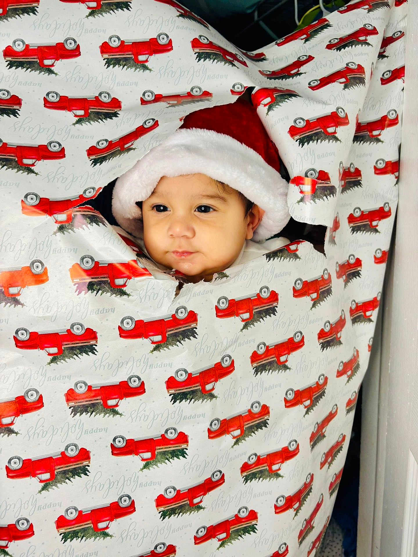 Ronald joined the competition — help win amazing prizes! baby, child, face, santa_hat, wrapping_paper, holiday, christmas, red_truck, cute, peek, present, festive, smile, portrait, indoors, holiday_season, celebration, holiday_decor, childhood, happy