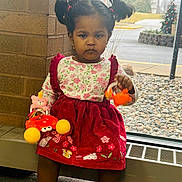 Moksha is registered to the contest to win money with this photo: toddler, child, girl, indoor, window, toys, pigtails, dress, red_dress, floral_pattern, serious_expression, shoes, carpet, radiator, brick_wall, winter, outside, rocks, decorations, person