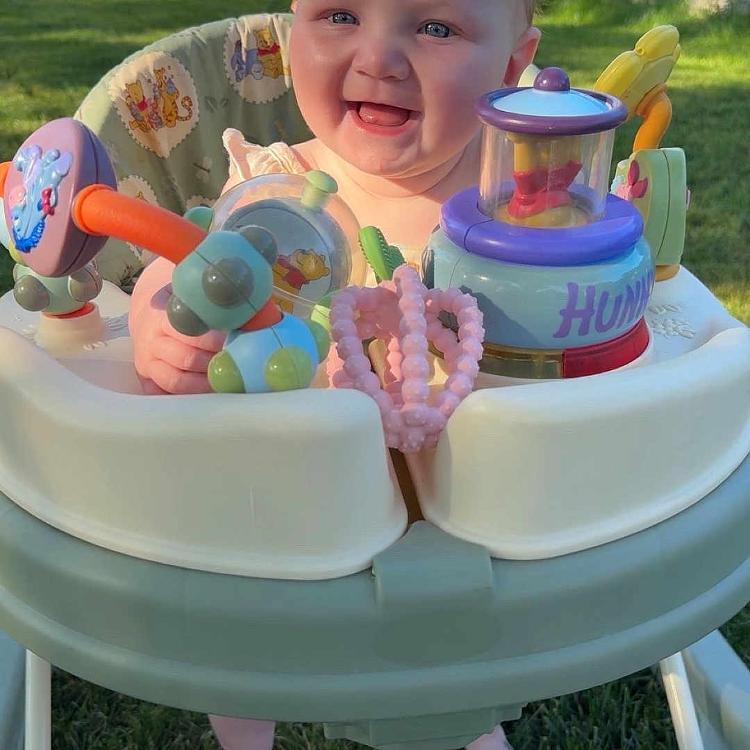 Sarraye joined the competition — help win amazing prizes! baby, blue_eyes, child, cute, daytime, fence, foot, garden, grass, happy, infant, outdoor, plastic_toy, playful, portrait, seat, smiling, sunlight, toy, walker