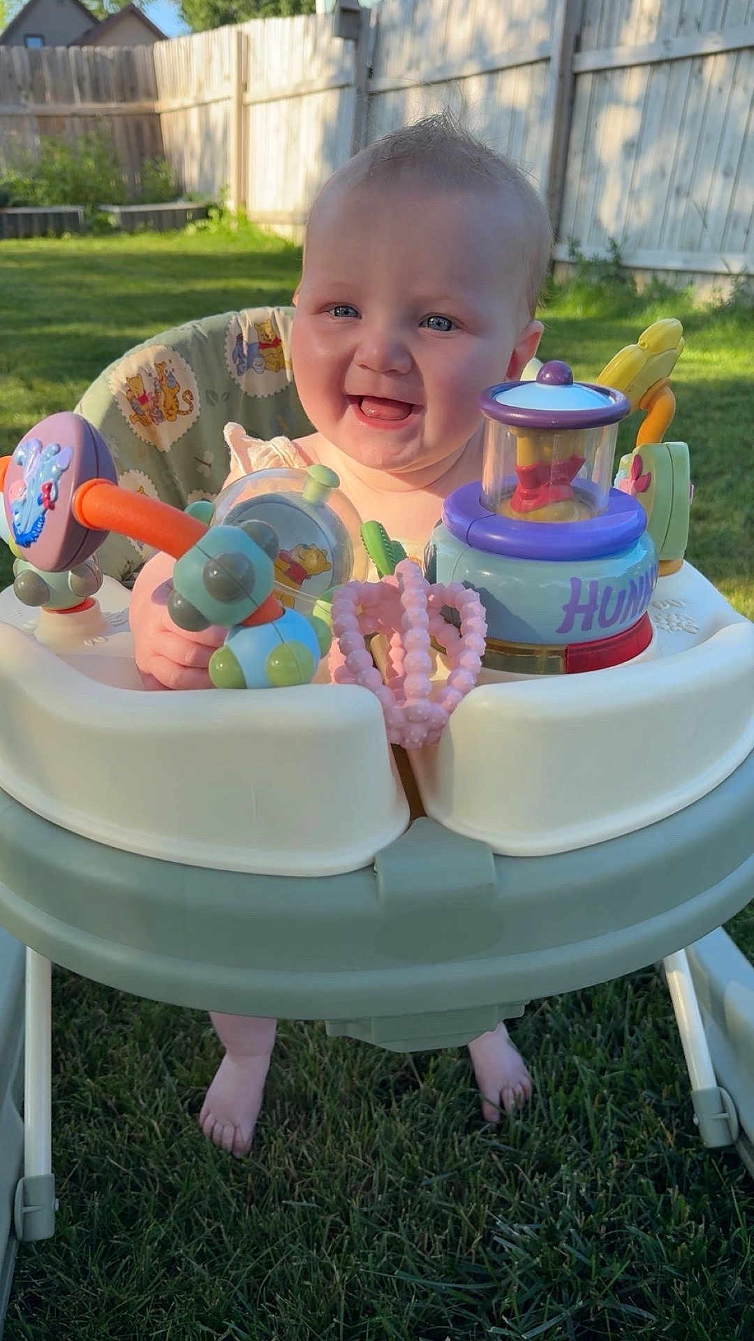 Sarraye joined the competition — help win amazing prizes! baby, blue_eyes, child, cute, daytime, fence, foot, garden, grass, happy, infant, outdoor, plastic_toy, playful, portrait, seat, smiling, sunlight, toy, walker