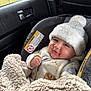 baby, infant, car_seat, hat, blanket, clothing, smile, face, person, indoor, window, rain, car_interior, seatbelt, warm, cute, child, cozy, soft, comfort