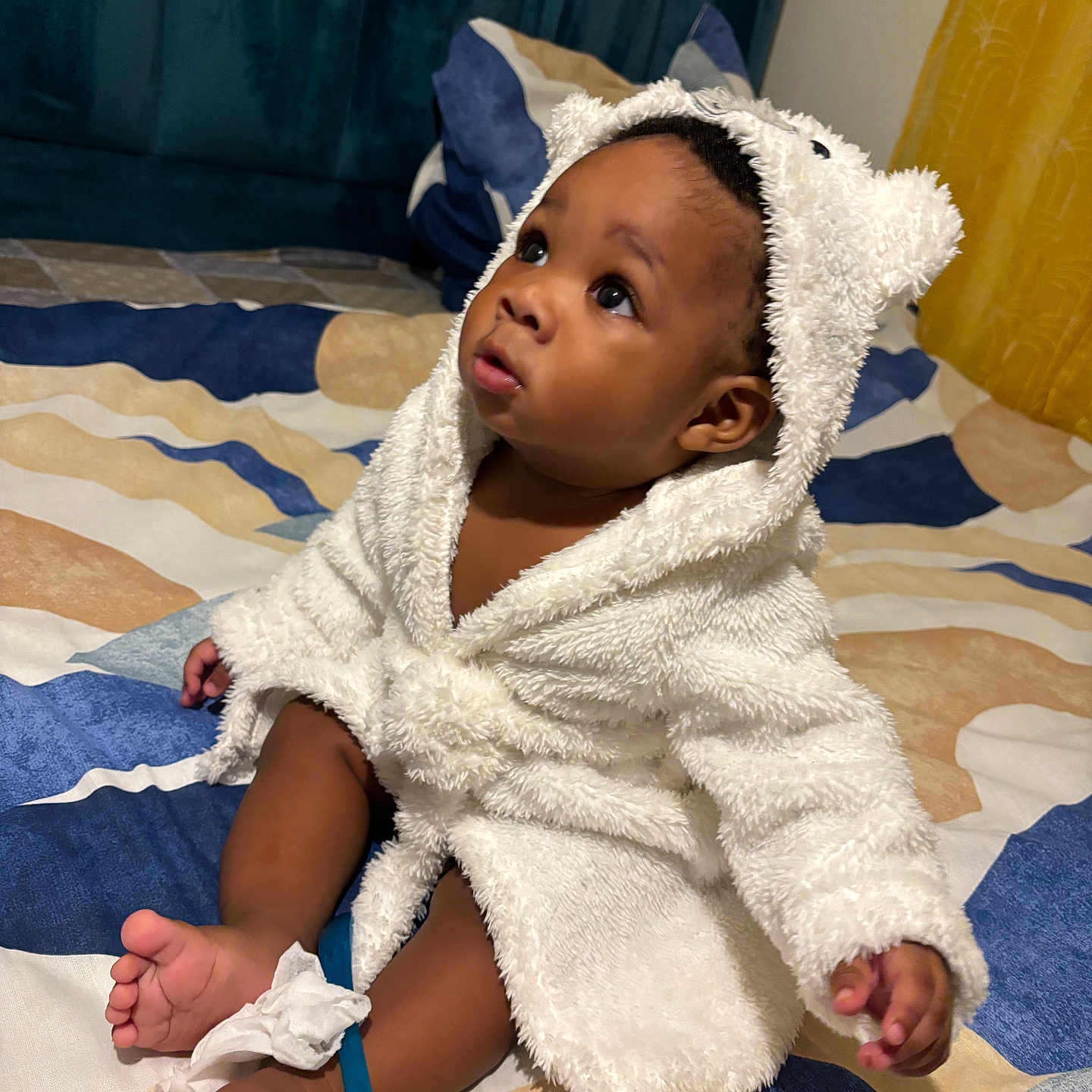 Sidiki participe au concours pour gagner de l'argent avec cette photo : baby, bed, bedspread, blue_spoon, child, curious, cute, foot, hood, indoor, infant, person, plush, robe, sitting, soft_texture, tissue, toes, white_robe, wide_eyes