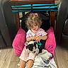 Oreo Lee joined the competition — help win amazing prizes! blanket, casual_clothing, child, cozy, curly_hair, dog, family, floor, furniture, home, indoor, pet, pink_chair, playing, puppy, seated, toddler, wooden_floor, wooden_table, young_child