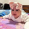 Sarah joined the competition — help win amazing prizes! baby, child, headband, pink_bow, white_clothing, blanket, indoor, bedroom, face, cute, smiling, toddler, lying_down, bright_eyes, curious, soft_lighting, closeup, portrait, colorful_blanket, cozy