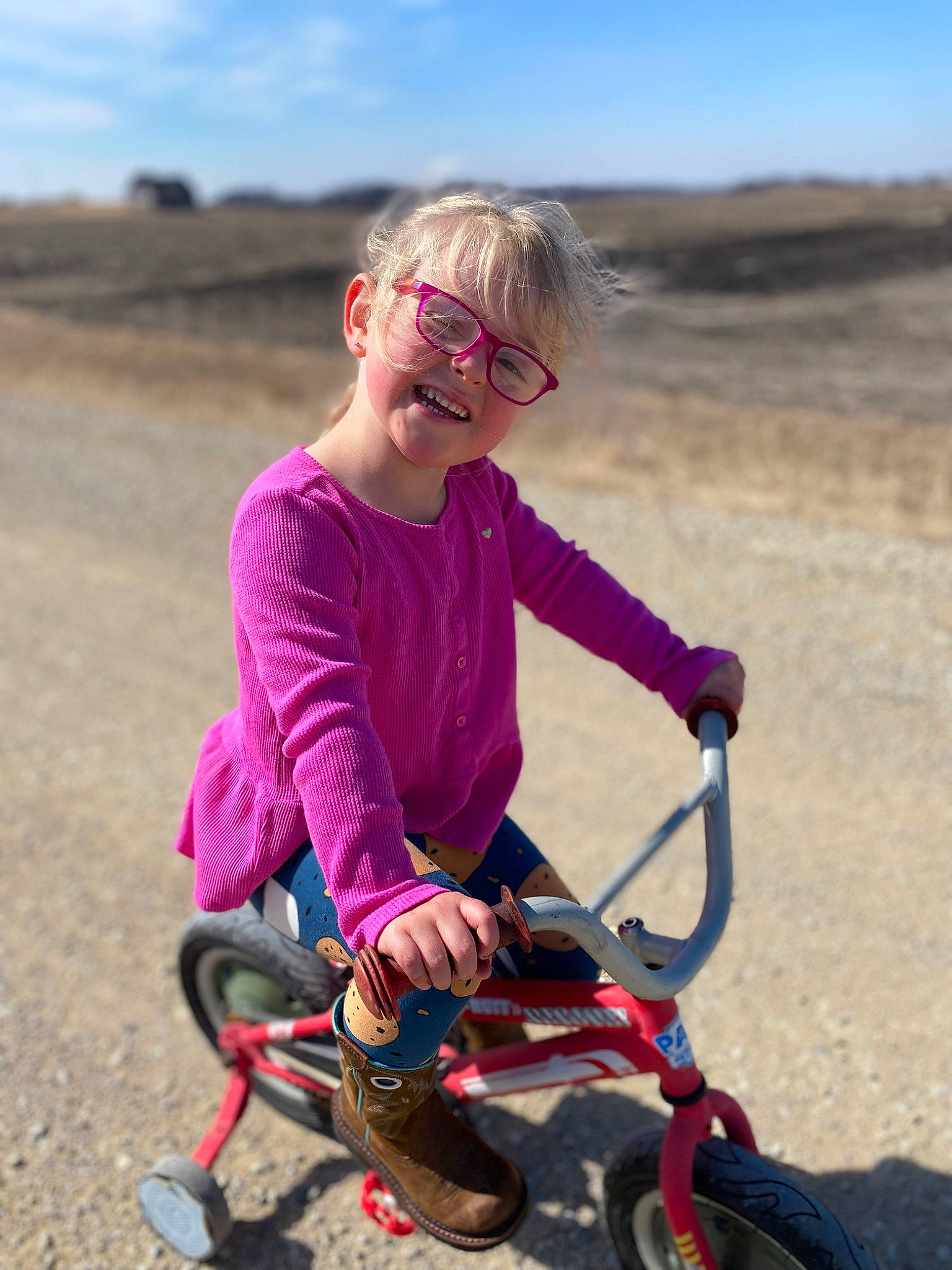 Kahlani-jean is registered to the contest to win money with this photo: bicycle_frame, bicycle_handlebar, bicycle_tire, bicycles_equipment_and_supplies, eyewear, fun, grass, happy, helmet, joy, landscape, leisure, person, personal_protective_equipment, recreation, sky, smile, sunglasses, tire, toddler