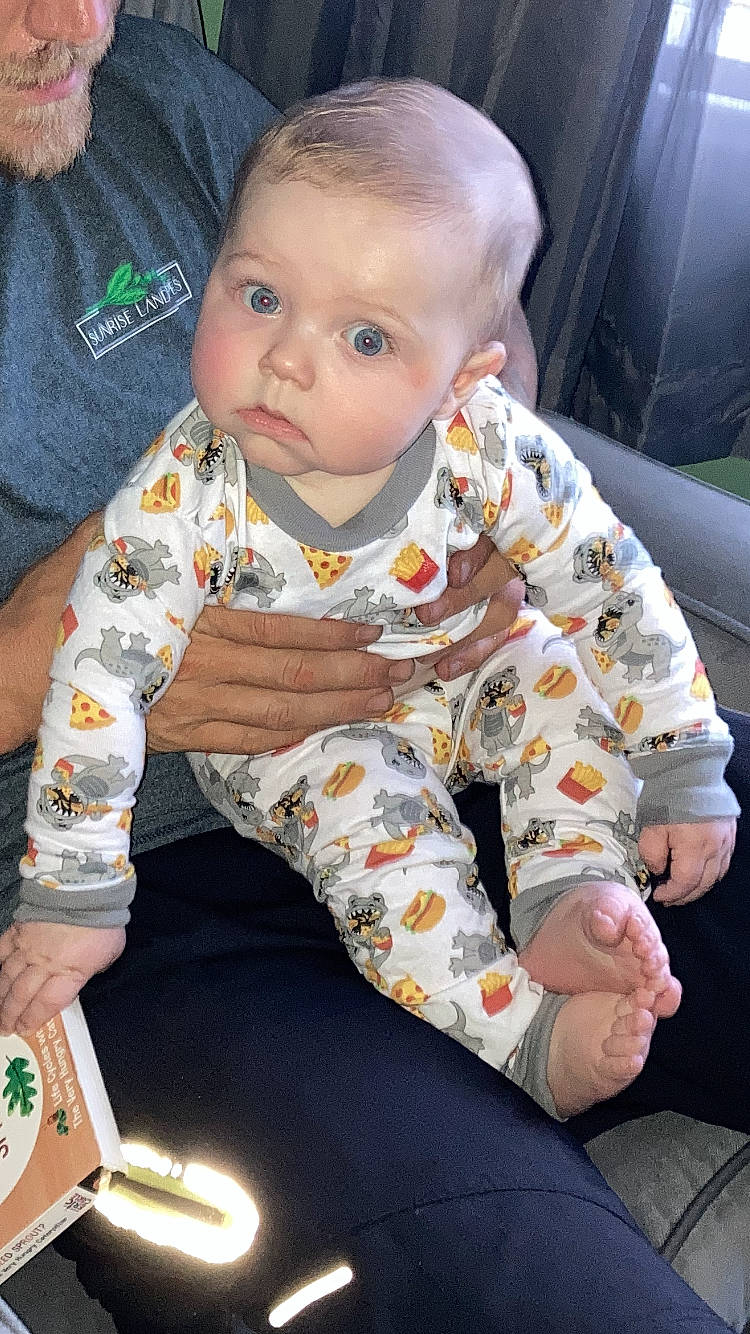 Sydney is registered to the contest to win money with this photo: baby, baby_toddler_clothing, cheek, child, collar, comfort, face, flooring, fun, hairstyle, happy, head, lap, mouth, person, sharing, sitting, skin, sleeve, t_shirt