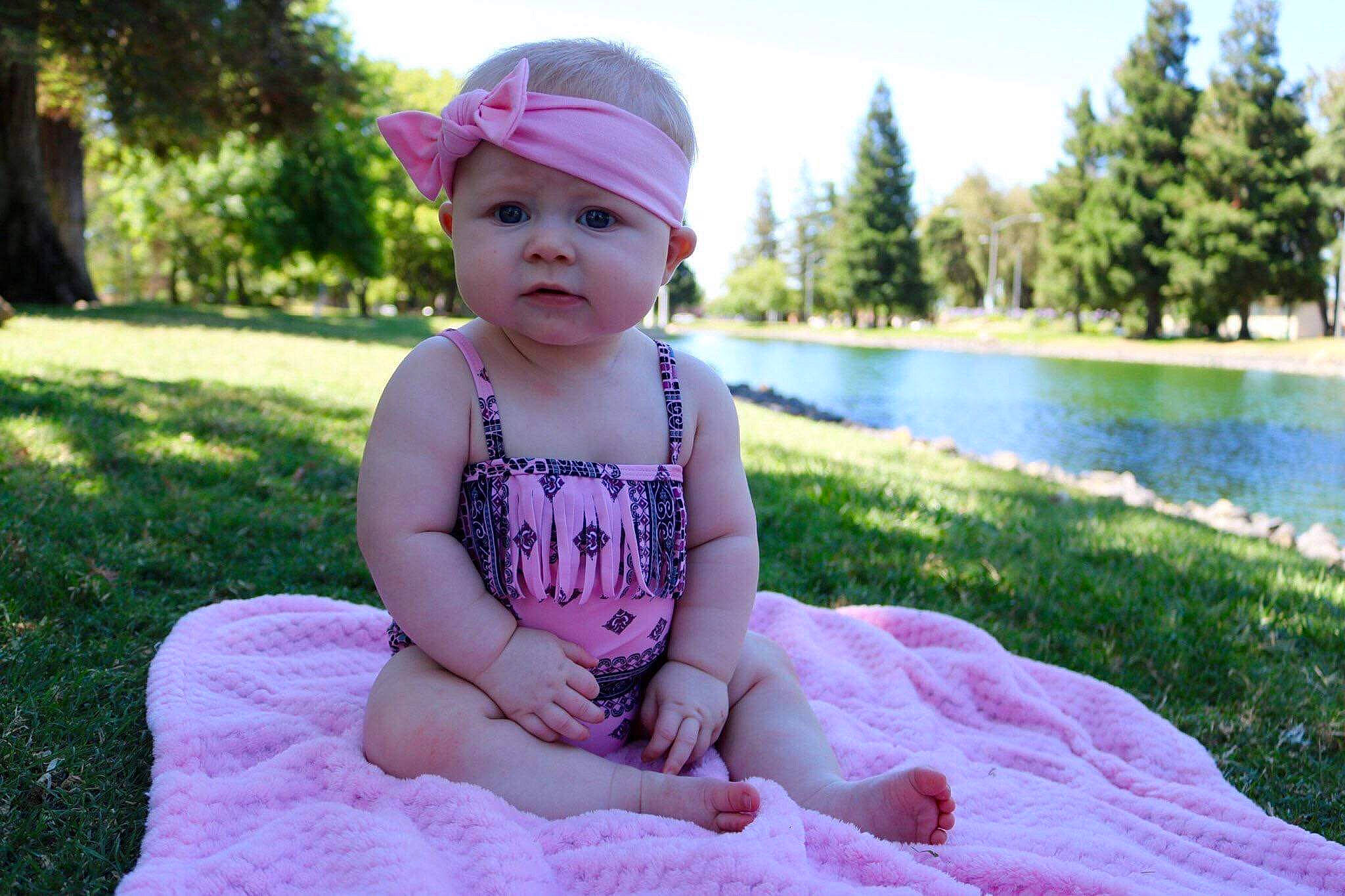 Mya is registered to the contest to win money with this photo: baby, child, dress, fashion_accessory, fun, grass, hair_accessory, headgear, headwear, lavender, person, pink, plant, purple, recreation, sitting, skin, smile, summer, toddler