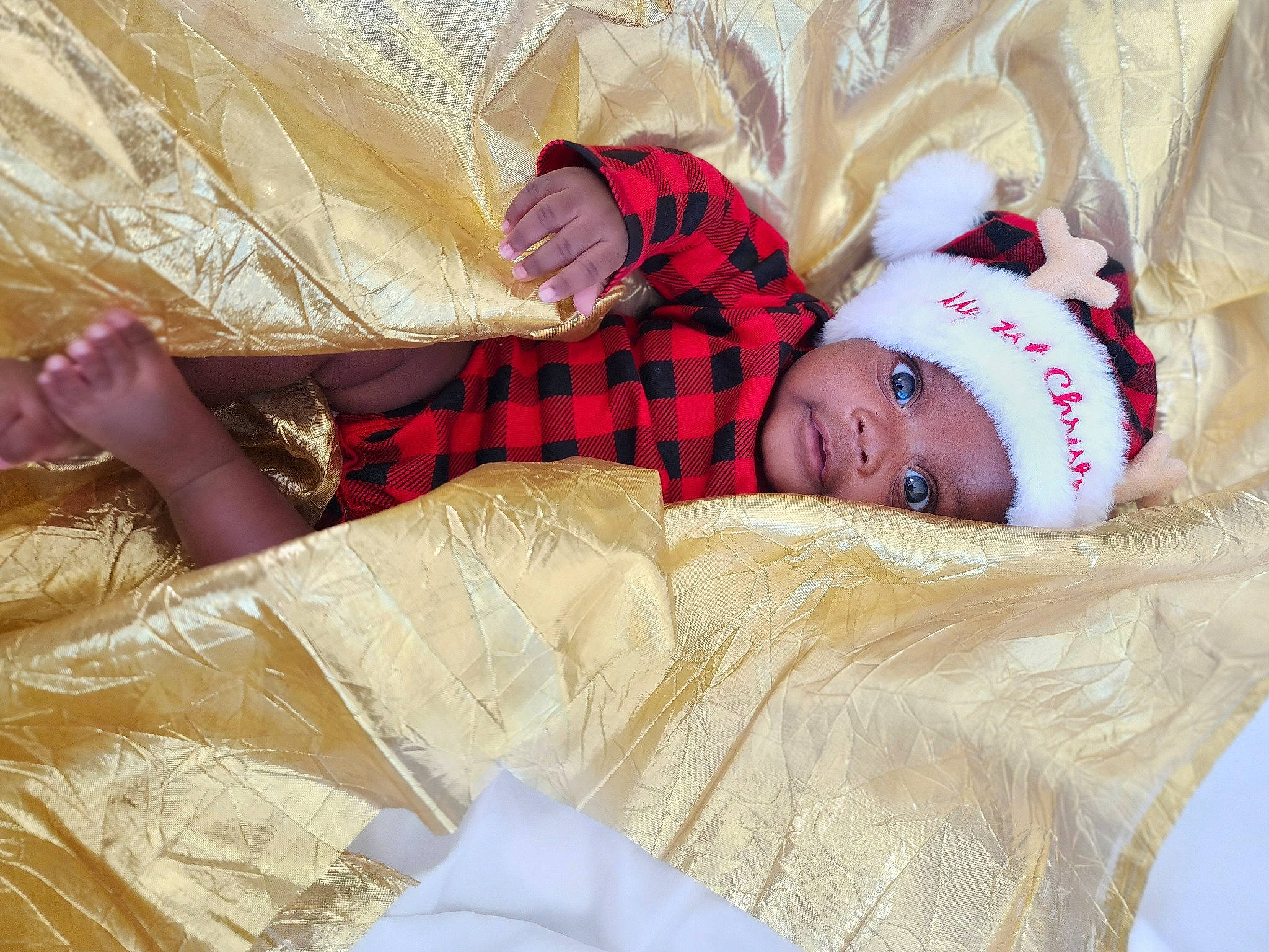 Devan is registered to the contest to win money with this photo: baby, baby_toddler_clothing, bedding, child, comfort, couch, fur, happy, human_leg, linens, pattern, person, plaid, room, sitting, sleeve, textile, thigh, toddler, tree