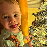 Kadence joined the competition — help win amazing prizes! toddler, child, smiling, happy, face, christmas_tree, ornament, holiday, festive, lights, indoor, cozy, curtain, decor, clothing, sleeve, young_child, joyful, closeup, portrait