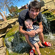 Kadence joined the competition — help win amazing prizes! man, toddler, waterfall, rocks, outdoor, sunny, smile, holding_hands, red_slides, striped_clothing, water, nature, playful, happy, child, person, summer, daylight, casual, fun