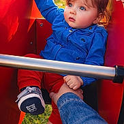 Maylonne a rejoint le concours — aidez-le/la à gagner de superbes lots ! baby, blue_jacket, bright_eyes, casual_clothing, child, curious, cute, daylight, grass, hand, holding, outdoor, person, play_equipment, playground, red_pants, safety_bar, sitting, sneakers, toddler