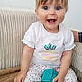 Iris participe au concours pour gagner de l'argent avec cette photo : baby, child, smiling, pigtails, blue_eyes, toy, couch, white_shirt, patterned_pants, socks, cute, indoors, happy, infant, seated, playful, young_child, person, portrait, bright
