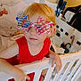 Elizabeth is registered to the contest to win money with this photo: american_flag_pattern, baby, baby_room, bedding, blonde_hair, child, crib, cute, face, furniture, glasses, hand, indoor, person, playful, portrait, red_clothing, star_shaped_glasses, toy, young_child