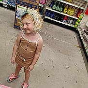 Elizabeth is registered to the contest to win money with this photo: aisle, blonde_hair, casual_wear, child, clothing, cute, flip_flops, floor, footwear, headwear, household_products, indoor, person, product_boxes, shelves, shopping, smile, store, tinsel, young_child