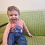toddler, child, smiling, sitting, couch, green_couch, jeans, tshirt, indoor, happy, face, hand, person, casual_clothing, young_child, cute, home, playful, light_skin, short_hair