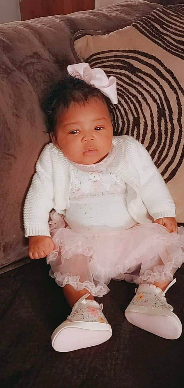 Y'Omi is registered to the contest to win money with this photo: baby, baby_toddler_clothing, cheek, child, dress, embellishment, eye, face, fashion_accessory, flash_photography, happy, human_body, lip, pattern, person, pink, skin, sleeve, sock, toddler