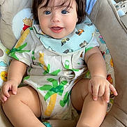 Josiah joined the competition — help win amazing prizes! baby, child, blue_eyes, smiling, sitting, cushion, seat, clothing, bib, patterned_fabric, disney, indoor, cute, happy, infant, barefoot, hand, foot, hair, portrait