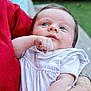 baby, infant, child, person, face, blue_eyes, white_clothing, arm, hand, skin, outdoor, garden, adult_hand, red_clothing, portrait, closeup, soft_light, cute, newborn, holding