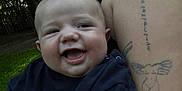 Alexander is registered to the contest to win money with this photo: baby, child, smiling, happy, person, tattoo, arm, outdoor, nature, grass, trees, clothing, sweater, love, face, closeup, portrait, skin, adult, holding