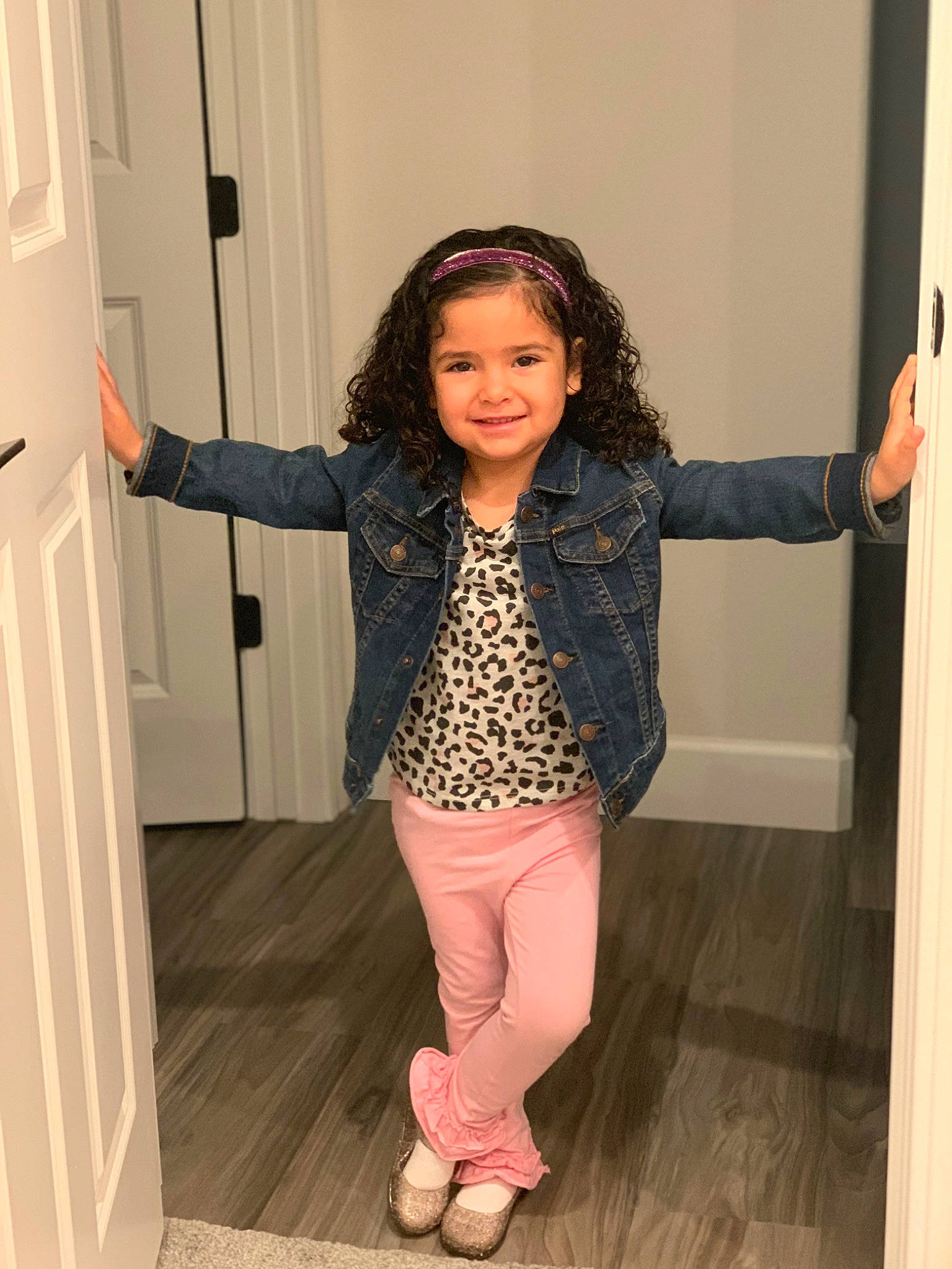 Isabella is registered to the contest to win money with this photo: beauty, door, fashion_design, floor, flooring, gesture, happy, hardwood, human_leg, joint, joy, knee, leg, person, shoulder, sleeve, smile, standing, thigh, toddler