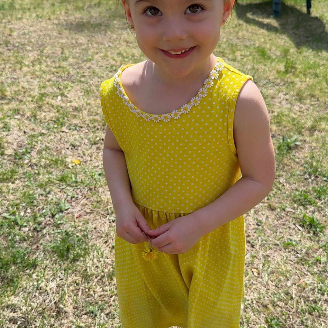 Amelia joined the competition — help win amazing prizes! bare_arms, casual, child, daylight, feet, flower, girl, grass, hair_bun, happy, nature, outdoor, playful, portrait, smiling, summer, sunny, unicorn_sandals, yellow_dress, young_child