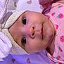 baby, child, infant, face, headband, bow, pink_clothing, strawberry_pattern, onesie, closeup, portrait, lying_down, blanket, rainbow_pattern, cute, wide_eyes, soft_texture, newborn, adorable, skin