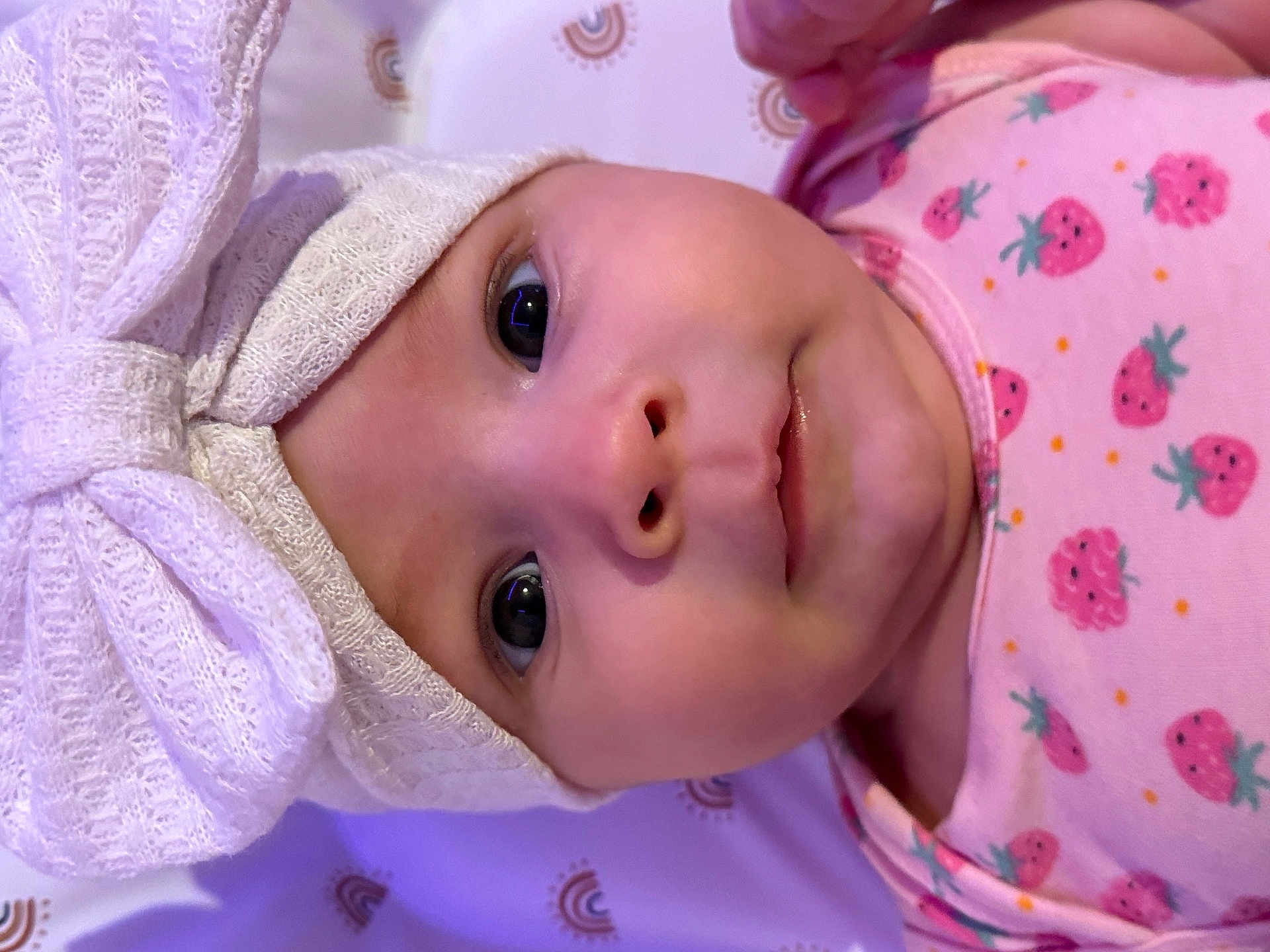 Arya participe au concours pour gagner de l'argent avec cette photo : baby, child, infant, face, headband, bow, pink_clothing, strawberry_pattern, onesie, closeup, portrait, lying_down, blanket, rainbow_pattern, cute, wide_eyes, soft_texture, newborn, adorable, skin
