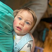 Deklan is registered to the contest to win money with this photo: blue_eyes, blurred_background, casual, child, close_up, clothing, curious, cute, face, holding, indoor, patterned_shirt, person, portrait, rosy_cheeks, soft_light, toddler, toy, wooden_floor, young