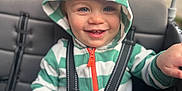 Deklan is registered to the contest to win money with this photo: baby, blue_eyes, blurred_background, child, clothing, cute, face, hand, happy, hoodie, orange_spikes, outdoor, person, portrait, seatbelt, sippy_cup, smiling, striped_clothing, stroller, toddler