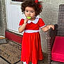 Ayla is registered to the contest to win money with this photo: child, girl, lollipop, red_dress, white_collar, curly_hair, red_bow, white_tights, white_shoes, wicker_chair, door, welcome_mat, concrete_floor, outdoor, halloween_decor, ghost_drawing, curious, standing, holding, holiday