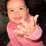 Ayla is registered to the contest to win money with this photo: child, toddler, smiling, pink_clothing, curly_hair, indoor, couch, happy, face, portrait, hand, sitting, cute, dimples, long_sleeves, pants, cozy, furniture, young_child, playful