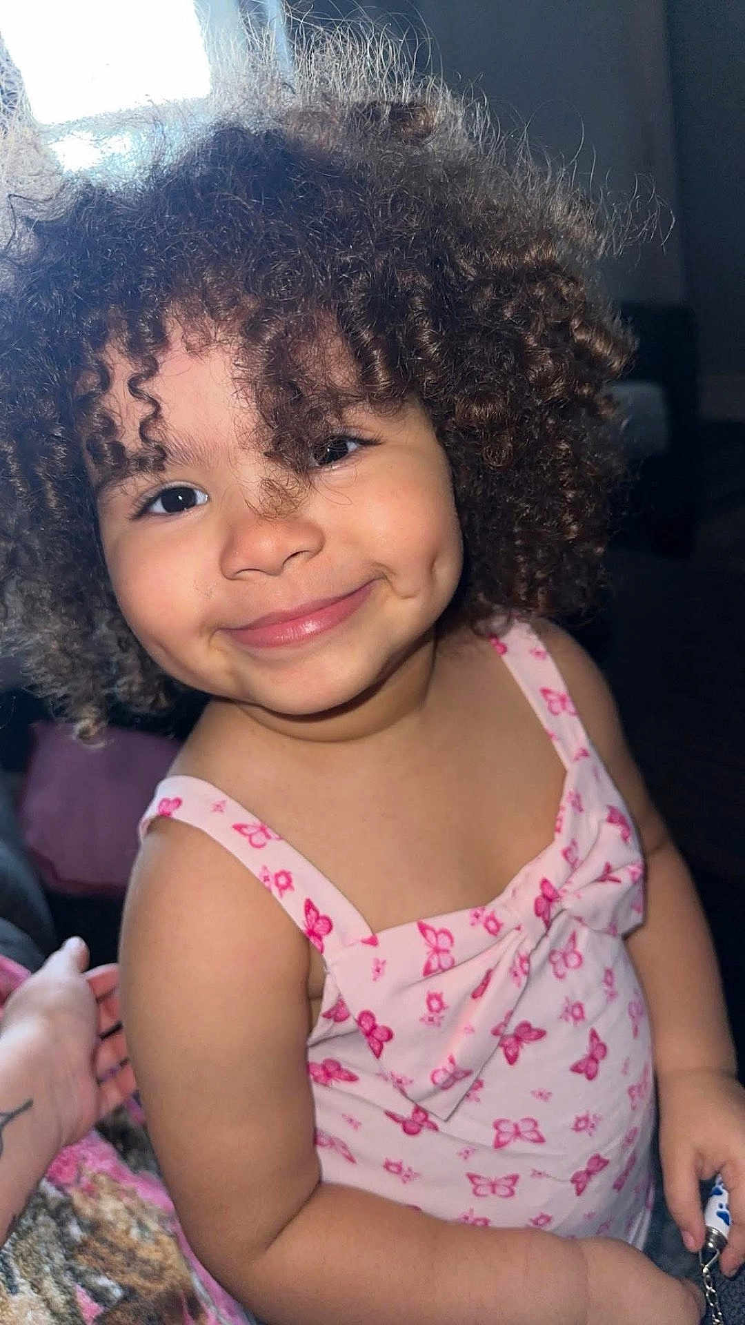 Ayla is registered to the contest to win money with this photo: child, toddler, curly_hair, smile, pink_dress, butterfly_pattern, indoor, portrait, cute, happy, person, face, dimples, skin, hand, clothing, young, female, fashion, childhood