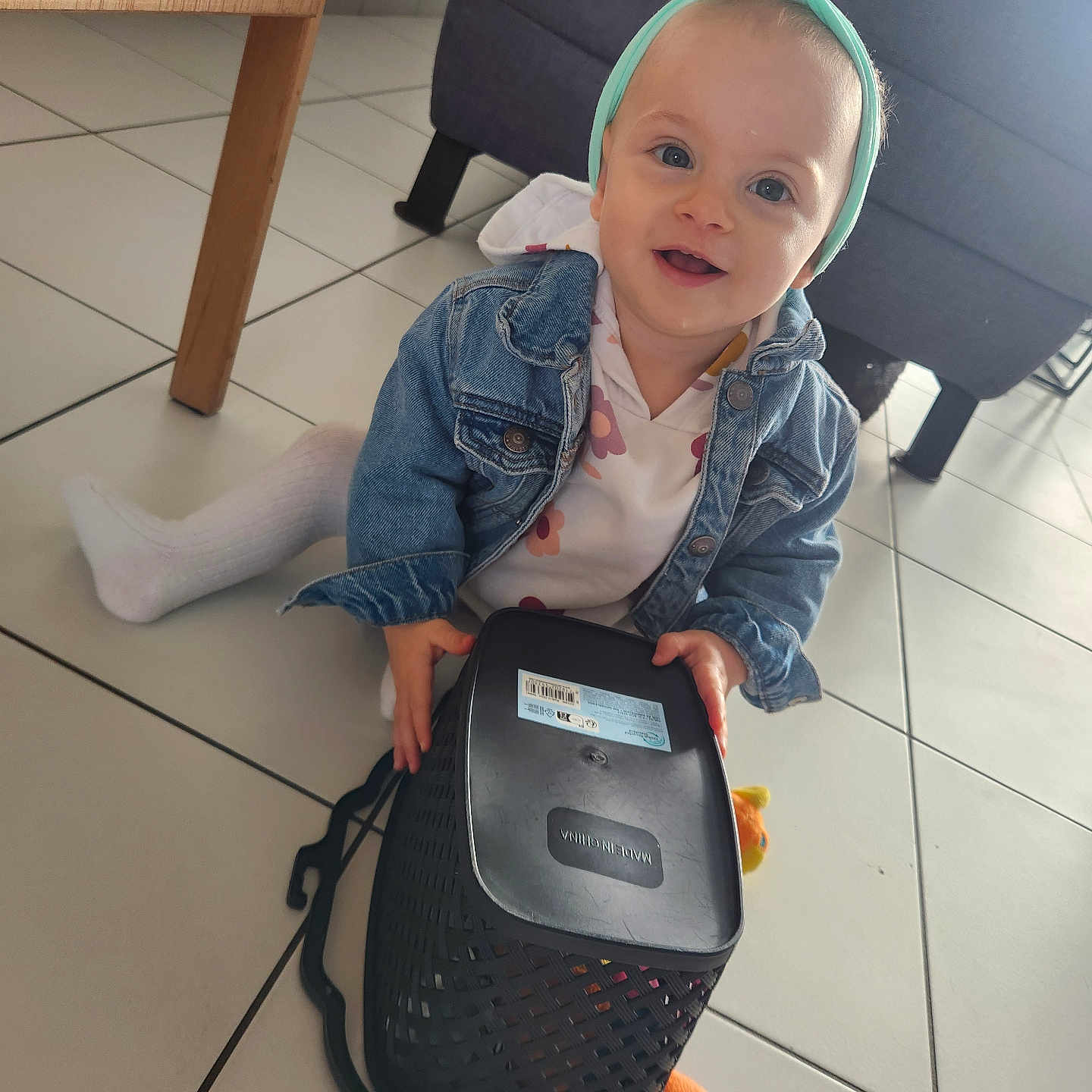 Zola a rejoint le concours — aidez-le/la à gagner de superbes lots ! baby, basket, child, couch, cute, denim_jacket, floor, furniture, happy, headband, indoor, person, playful, sitting, smiling, table_leg, tile_floor, toddler, toy, white_tights