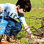 child, boy, outdoor, grass, bucket, searching, spring, easter, boots, crouching, casual_clothing, sunlight, nature, play, activity, young, daylight, garden, fun, curious