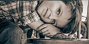 Oliver Lee joined the competition — help win amazing prizes! child, face, hands, wood, table, plaid_shirt, sepia, portrait, resting, young, curly_hair, furniture, casual_clothing, close_up, thoughtful, indoor, relaxed, natural_light, person, expression