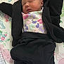 newborn, baby, sleeping, blanket, butterfly, patterned, clothing, black_jacket, black_pants, white_socks, infant, lying_down, cozy, cute, peaceful, indoors, soft_lighting, fabric, babywear, portrait