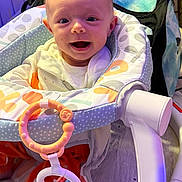 Aviya is registered to the contest to win money with this photo: accessory, baby, baby_seat, bright, child, clothing, colorful, comfort, cute, face, floor, happy, indoors, infant, joy, person, playtime, seat, smiling, toy_rings