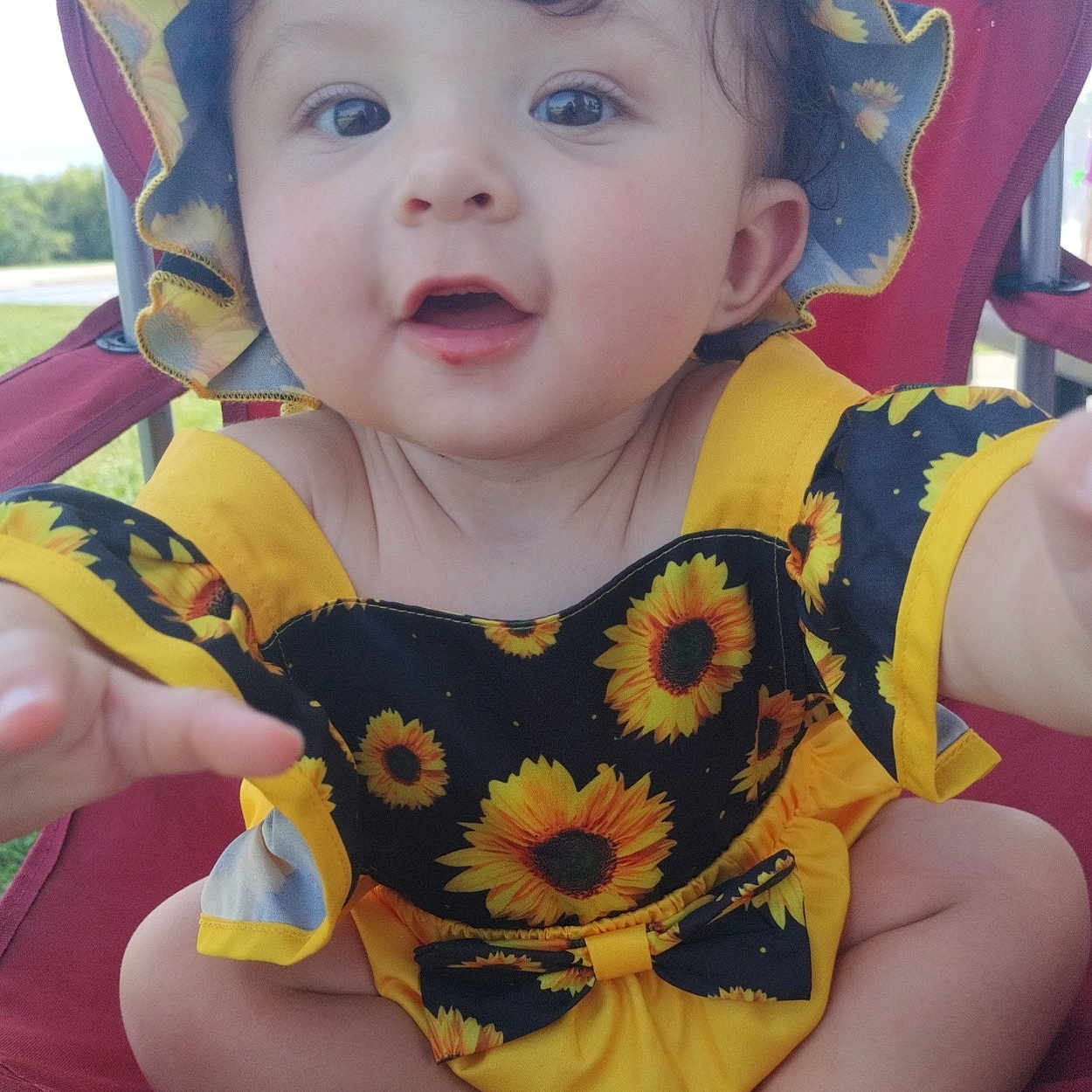 Ashiah joined the competition — help win amazing prizes! baby, child, clothing, cute, expression, face, foot, happy, hat, infant, nature, outdoor, person, portrait, red_chair, sitting, skin, smiling, summer, sunflower