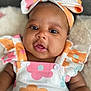 Xamira is registered to the contest to win money with this photo: baby, infant, child, face, headband, bow, clothing, floral_pattern, cute, portrait, skin, eyes, mouth, soft_texture, fabric, sleeveless, colorful, pink, orange, white